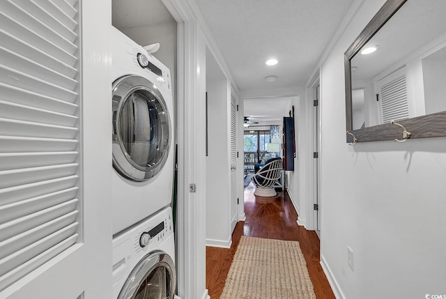 washroom featuring stacked washing maching and dryer, ceiling fan, and dark hardwood / wood-style flooring