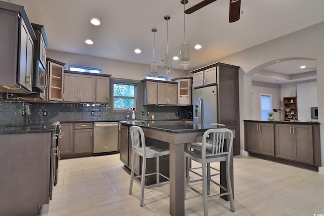 kitchen featuring a center island, hanging light fixtures, appliances with stainless steel finishes, a kitchen breakfast bar, and decorative backsplash