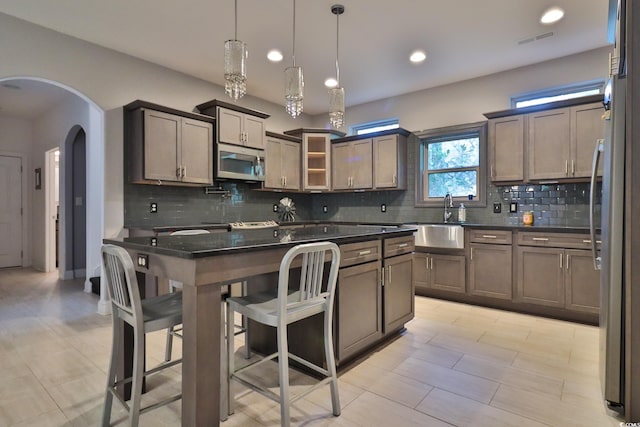 kitchen featuring pendant lighting, sink, stainless steel appliances, and a kitchen island