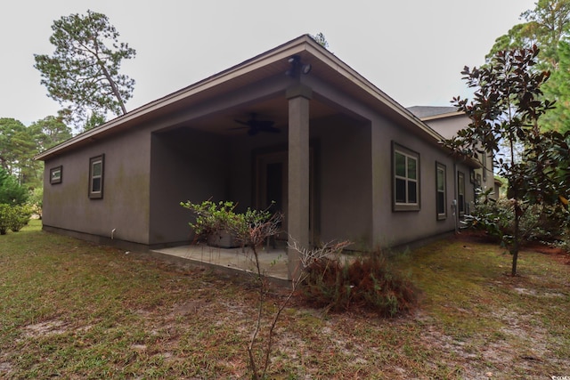 view of side of home featuring a lawn, a patio, and ceiling fan