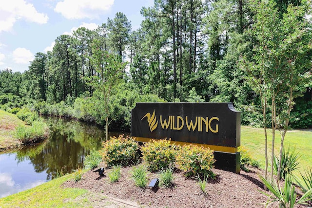 community / neighborhood sign with a water view and a lawn