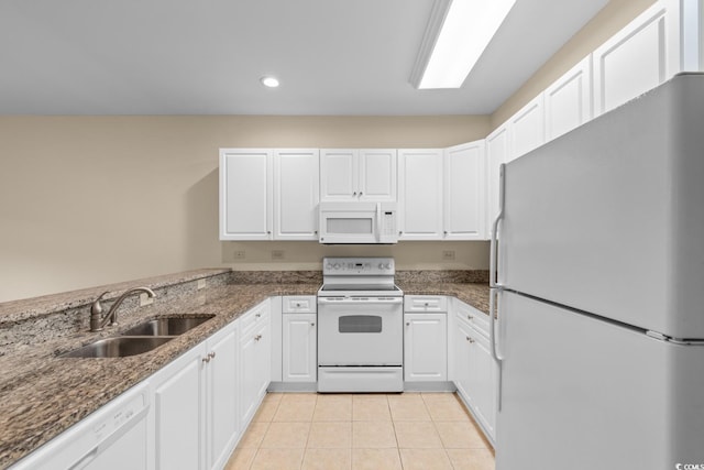 kitchen with sink, dark stone countertops, light tile patterned floors, white appliances, and white cabinets