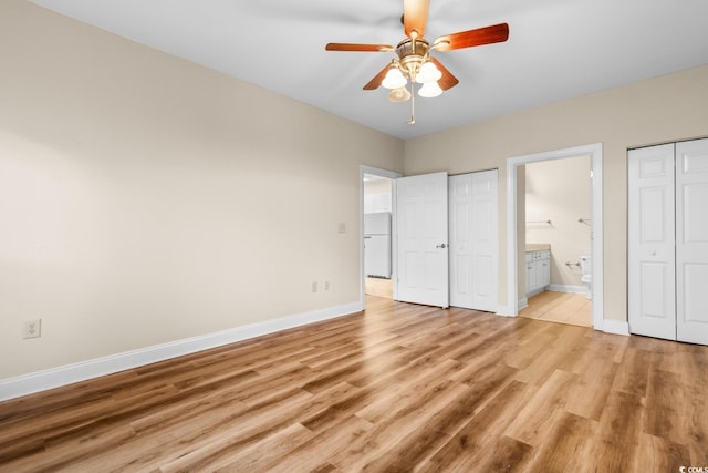 unfurnished bedroom featuring light wood-type flooring, ensuite bath, ceiling fan, and white fridge