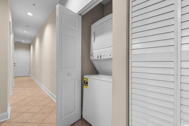 laundry area featuring stacked washing maching and dryer and light tile patterned floors