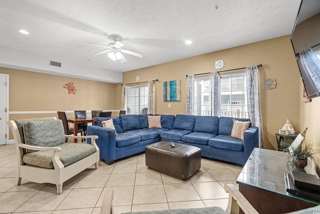 tiled living room with ceiling fan and a textured ceiling