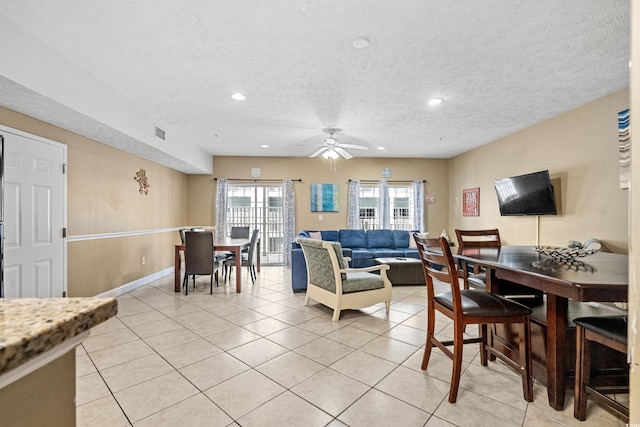 living room with a textured ceiling, light tile patterned floors, and ceiling fan