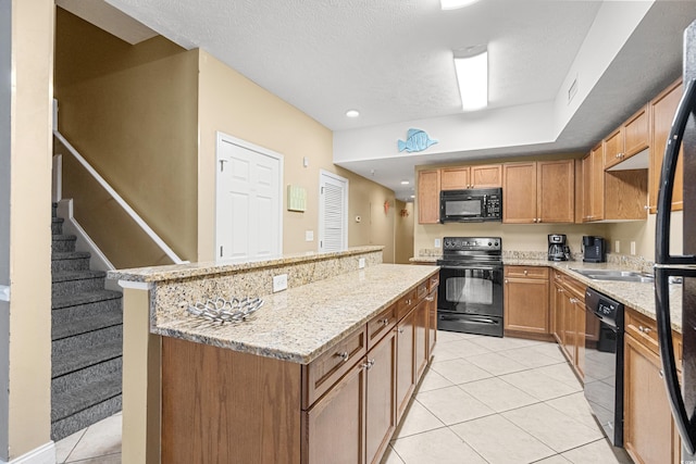 kitchen featuring a textured ceiling, light tile patterned floors, black appliances, and light stone counters