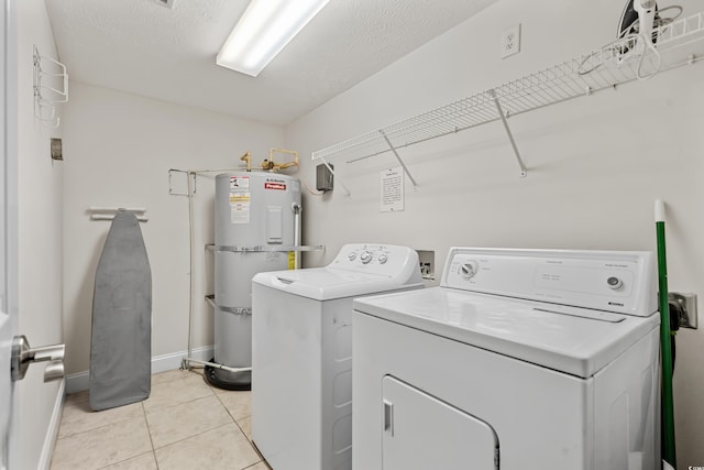 washroom with washer and clothes dryer, a textured ceiling, water heater, and light tile patterned flooring