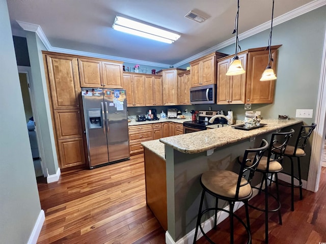 2347 Devine St, Georgetown, SC 29440 - kitchen with a kitchen bar, appliances with stainless steel finishes, a peninsula, light wood finished floors, and ornamental molding