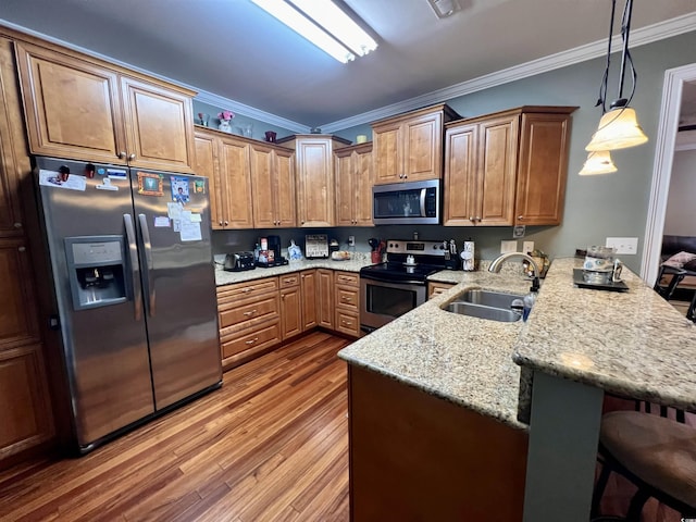 kitchen with crown molding, sink, appliances with stainless steel finishes, kitchen peninsula, and a breakfast bar area