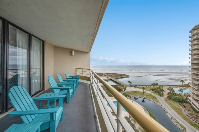 balcony with a water view and a view of the beach