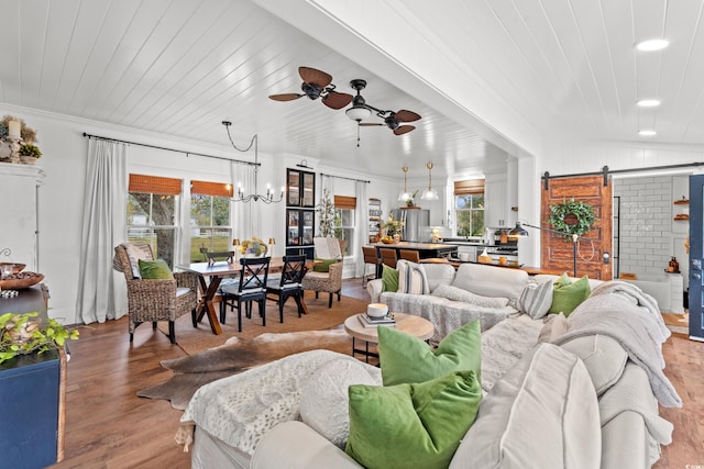 living room with a wealth of natural light, a barn door, light hardwood / wood-style floors, and ceiling fan with notable chandelier