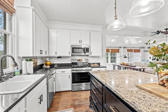 kitchen featuring stainless steel appliances, light hardwood / wood-style floors, sink, hanging light fixtures, and white cabinets