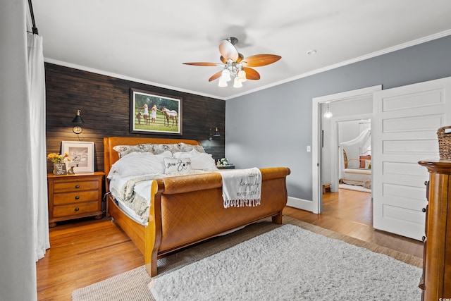 bedroom featuring light hardwood / wood-style flooring, wood walls, ceiling fan, and crown molding