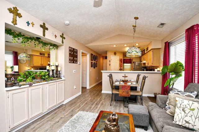 living room with a textured ceiling, light hardwood / wood-style flooring, and vaulted ceiling