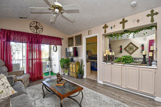 living room featuring a textured ceiling, ceiling fan, hardwood / wood-style floors, and vaulted ceiling