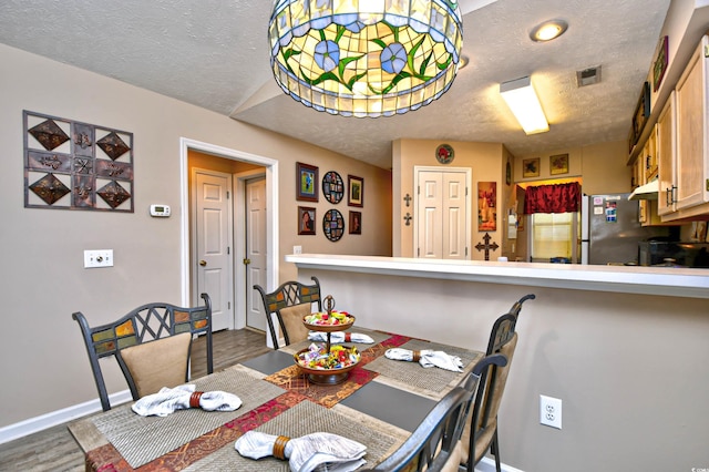 dining room with wood-type flooring and a textured ceiling