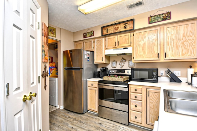 kitchen with a textured ceiling, light hardwood / wood-style floors, washer / dryer, and stainless steel appliances