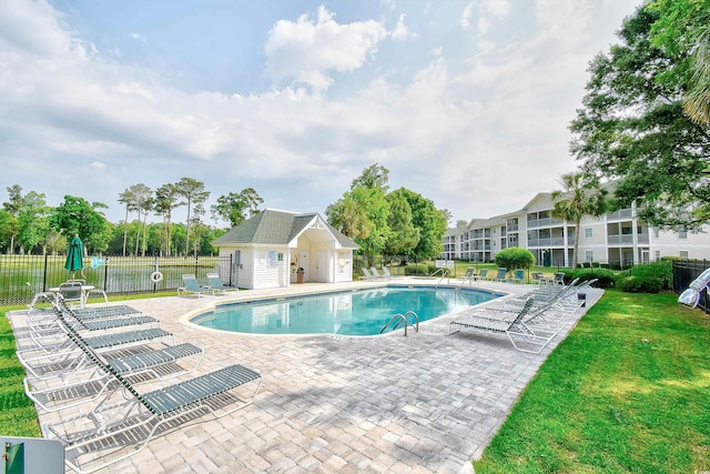 view of swimming pool featuring an outdoor structure, a patio, and a yard