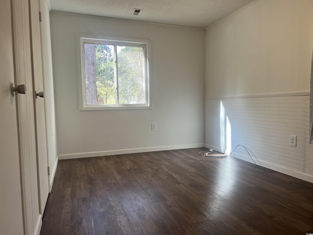 spare room with dark hardwood / wood-style floors and crown molding