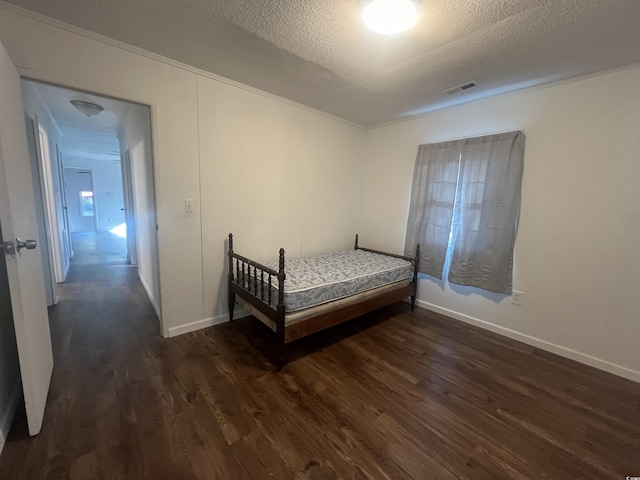 bedroom with a textured ceiling and dark hardwood / wood-style floors