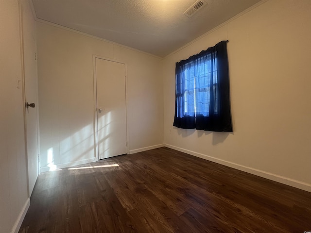 spare room with dark wood-type flooring, crown molding, and a textured ceiling