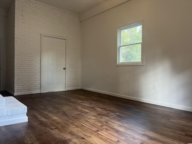 unfurnished bedroom with dark wood-type flooring, brick wall, and ornamental molding