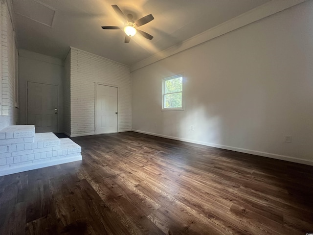 unfurnished room with ceiling fan, brick wall, and dark hardwood / wood-style floors