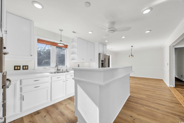 kitchen with white cabinetry, appliances with stainless steel finishes, hanging light fixtures, and light hardwood / wood-style flooring