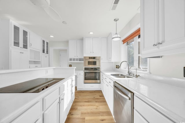 kitchen with white cabinetry, sink, pendant lighting, and appliances with stainless steel finishes