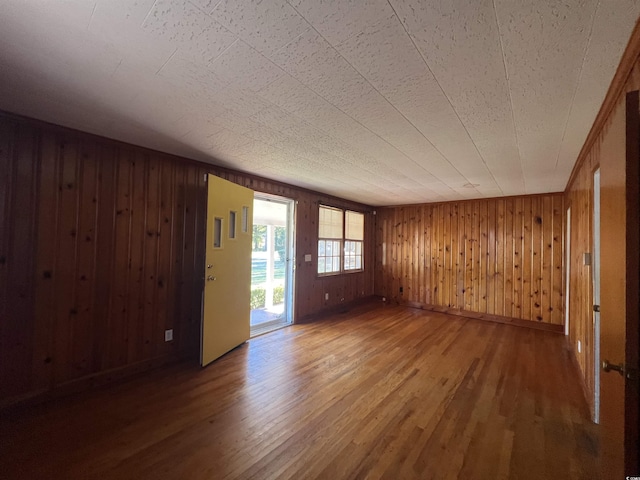 unfurnished room with wooden walls, wood finished floors, and baseboards