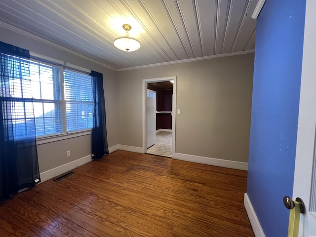 unfurnished room featuring visible vents, baseboards, wood finished floors, and crown molding