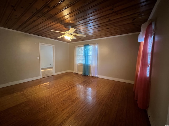 unfurnished room featuring wood ceiling, wood finished floors, baseboards, and ornamental molding