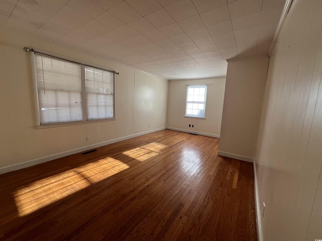 spare room featuring visible vents, baseboards, and wood finished floors