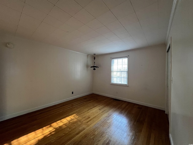 spare room with baseboards, wood finished floors, and ornamental molding