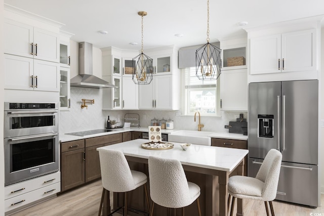 8479 Duke Pl Unit 34, Myrtle Beach, SC 29572 - kitchen featuring appliances with stainless steel finishes, wall chimney exhaust hood, a chandelier, white cabinets, and tasteful backsplash