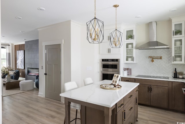8479 Duke Pl Unit 34, Myrtle Beach, SC 29572 - kitchen with wall chimney exhaust hood, black electric cooktop, stainless steel double oven, tasteful backsplash, and a kitchen bar