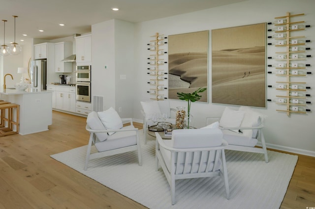 living room featuring sink and light hardwood / wood-style flooring