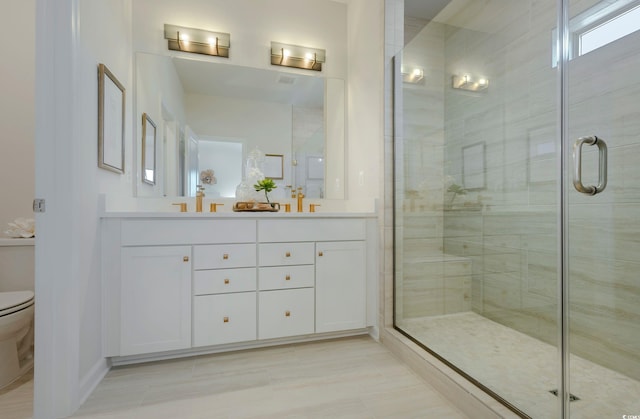 bathroom with vanity, toilet, and a shower with door