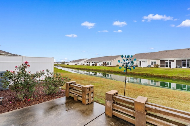 view of community with a patio area, a yard, and a water view