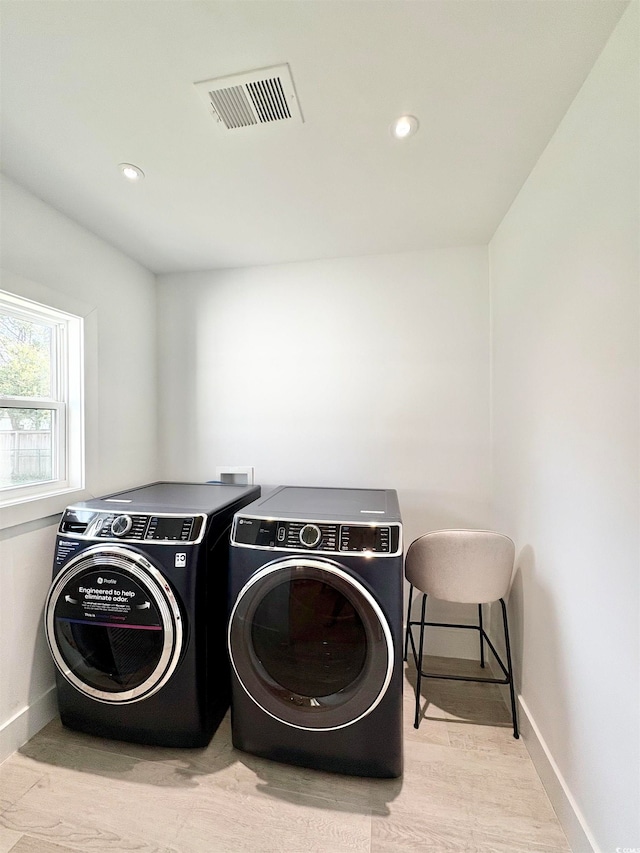 clothes washing area featuring washing machine and dryer and light hardwood / wood-style flooring