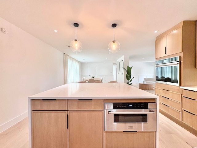 kitchen featuring light hardwood / wood-style floors, decorative light fixtures, light brown cabinetry, and oven