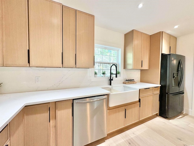 kitchen with stainless steel dishwasher, light brown cabinetry, black fridge with ice dispenser, and tasteful backsplash