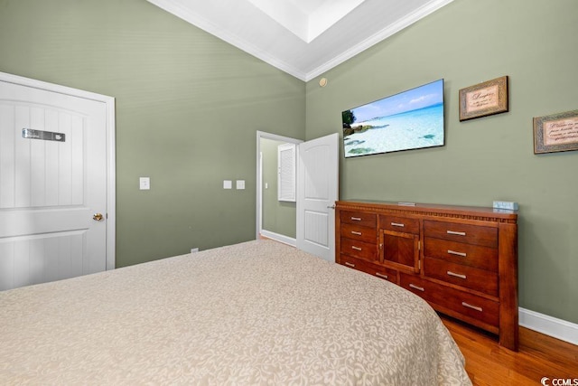 bedroom featuring hardwood / wood-style floors, lofted ceiling, and crown molding