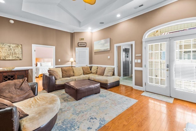 living room featuring french doors, light hardwood / wood-style flooring, lofted ceiling, and crown molding