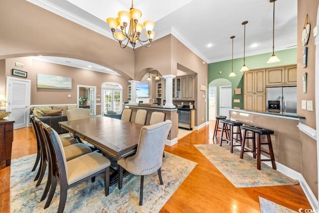 dining room with crown molding, light wood-type flooring, and a notable chandelier