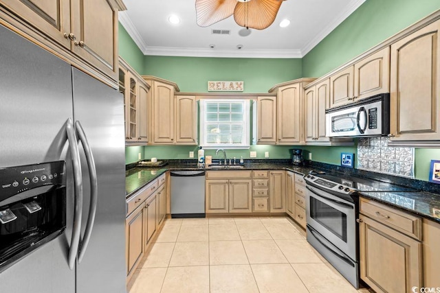 kitchen featuring sink, dark stone countertops, light tile patterned floors, light brown cabinetry, and stainless steel appliances