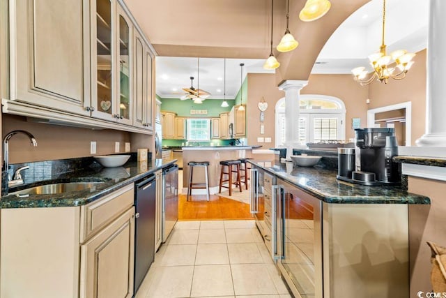 kitchen with ceiling fan with notable chandelier, sink, hanging light fixtures, light tile patterned floors, and decorative columns