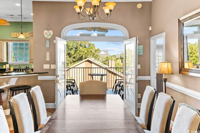 dining area featuring a high ceiling, hardwood / wood-style flooring, an inviting chandelier, and sink