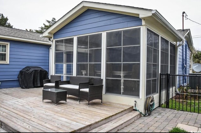 wooden deck with area for grilling, a sunroom, and an outdoor living space